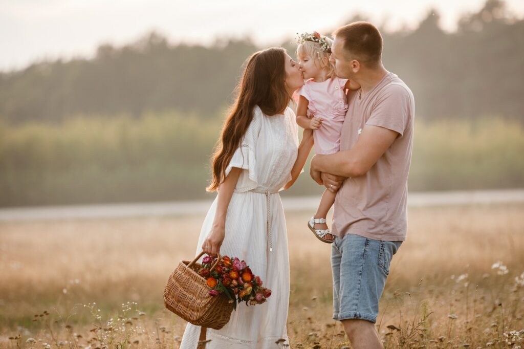 Ein glückliches Paar mit ihrem Kind in der idyllischen Landschaft, symbolisiert familiäre Harmonie und Zusammengehörigkeit.