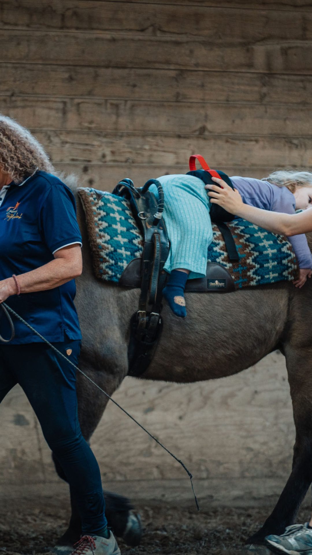 Ein behindertes Mädchen reitet auf einem Pferd als Teil der Hippotherapie-K bei Coaching Zeitgeschenk.