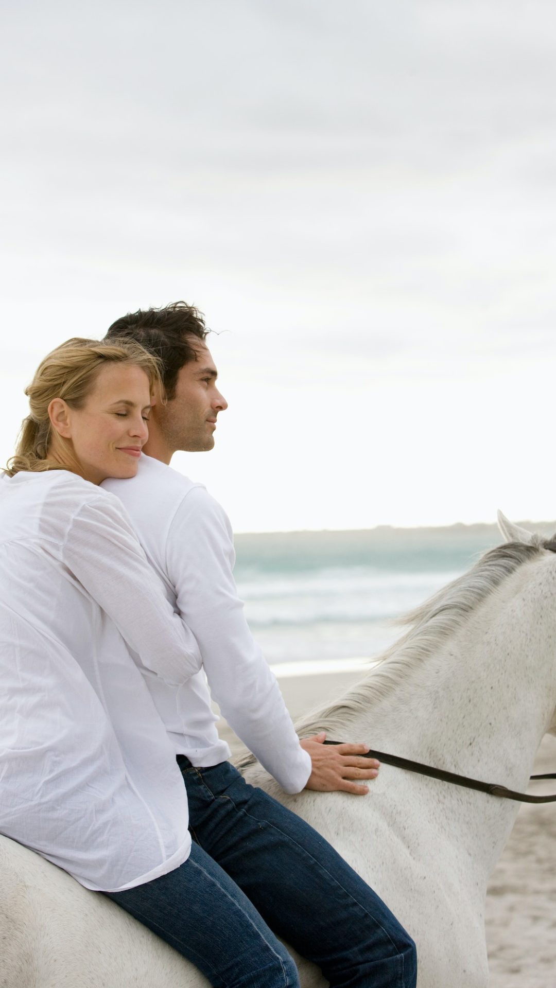 Ein Paar, das gemeinsam auf einem Pferd reitet, während einer Ehepaar-Coaching-Sitzung bei Coaching Zeitgeschenk.
